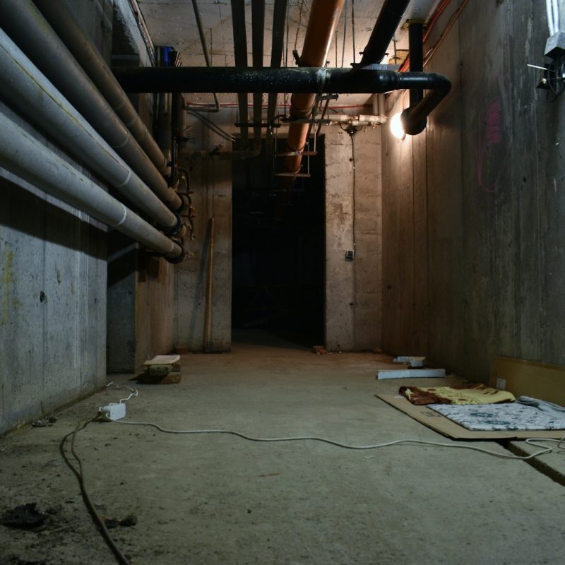 a dark room with pipes and a sheet of paper on the floor